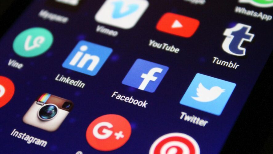 Close-up of a smartphone screen showing various social media app icons such as Facebook and Twitter.